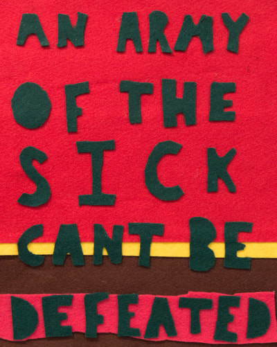 felt banner with text in green that says an army of the sick can’t be defeated, on a red background that is on the top 3/4ths of the image, with a yellow stripe then brown, and a pink strip on top of the brown.